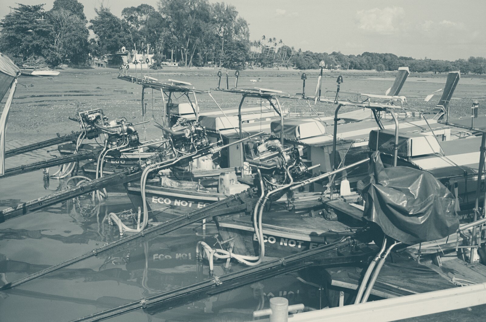 Several longtail boats docked at a muddy shore