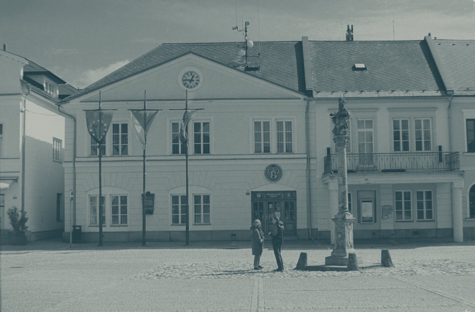 European town square with historic building, monument, and people