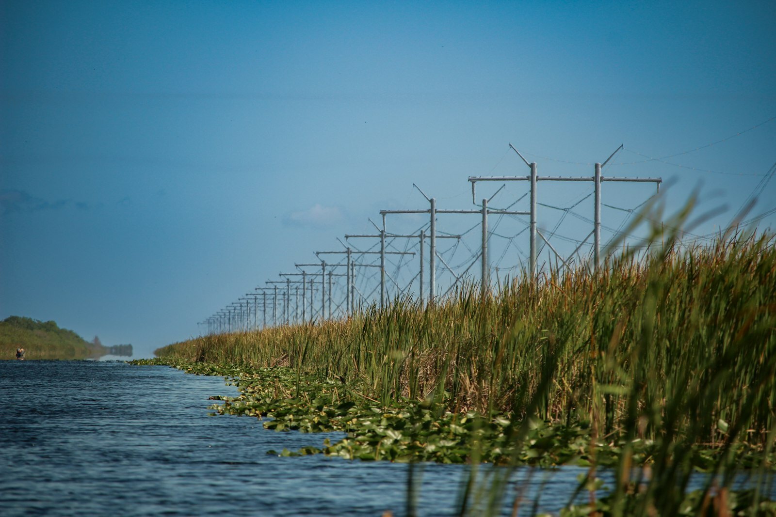 a row of power lines next to a body of water
