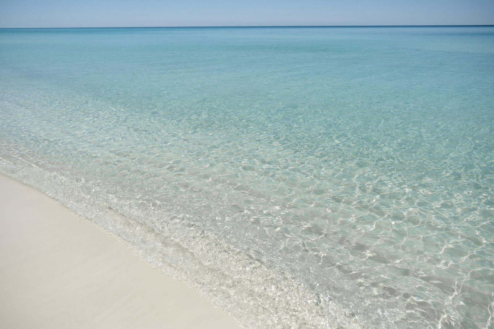 Beautiful turquoise water gently washes onto a sandy beach.